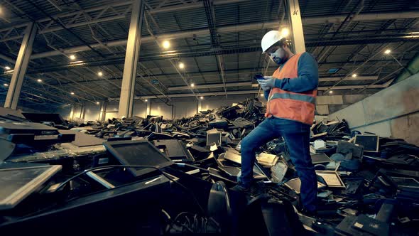 Discarded Monitors and a Male Dumpsite Worker Standing Near