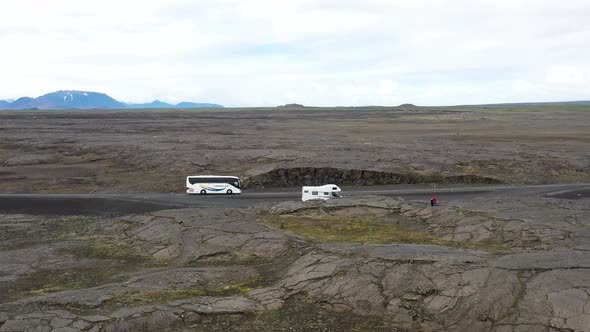 Recreational Vehicle and a tour bus located in lava field in Iceland with drone video moving forward