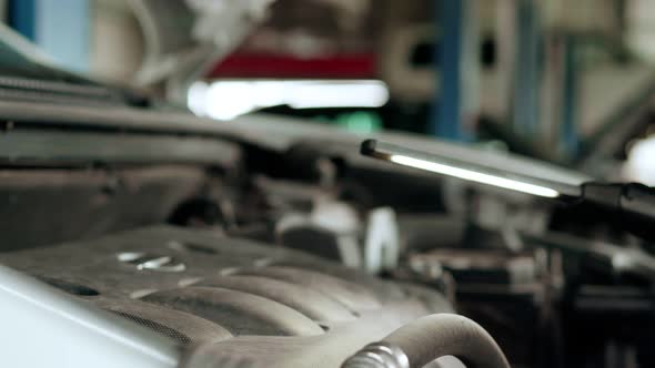 Mechanic Inspects Engine with a Flashlight