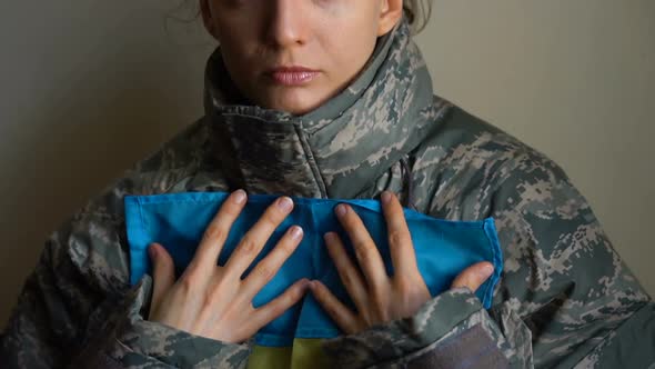 Young Female Soldier is Holding Ukrainian Flag with Love and Anxiety Due to Escalation Military