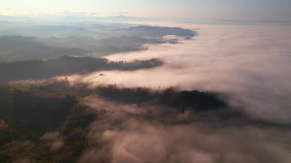 4K aerial view over mountain at sunrise in heavy fog. golden morning sunlight