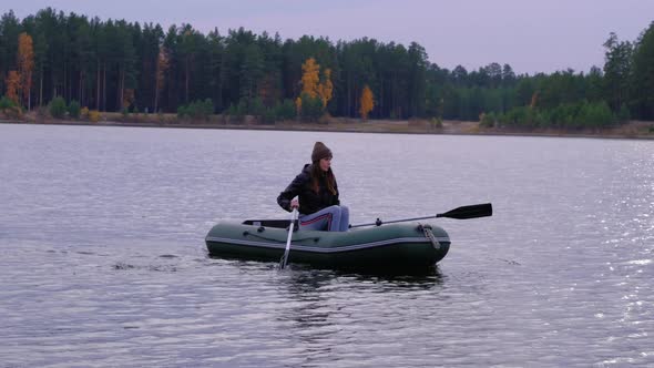 A Female Sportsman Rows and Swims on a Rubber Boat on Lake