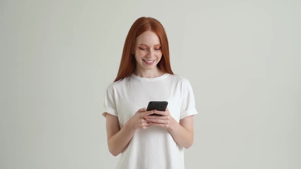 Portrait of Serious Attractive Young Woman Typing Online Message Using Mobile Phone on White