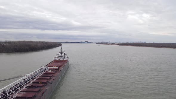 Massive freighter vessel in industrial crane on Detroit river, aerial fly over view
