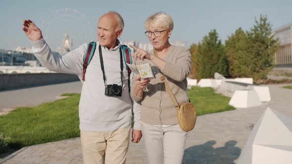 Elderly Couple Tourists Walking in Nice City Looking at Map and Discussing Trip on Summer Day