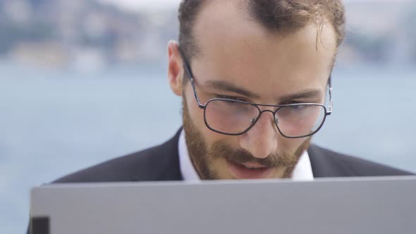 Businessman working on laptop outdoors.