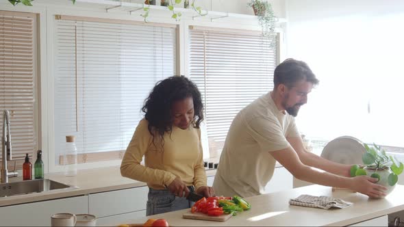 Young Multiethnic Couple in the Kitchen While Cooking and Cleaning