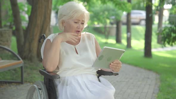 Portrait of Excited Disabled Caucasian Woman Talking at Selfie Camera on Tablet. Middle Shot of