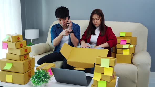 couple online entrepreneur talking on a mobile and packing parcel box at home office