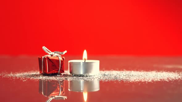 View of candle burning next to little christmas present