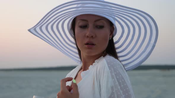 Elegant Woman with Glass of Wine Resting on Beach at Sunset