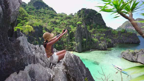 Woman Sitting On Limestone Rocks Taking Photo With Smartphone