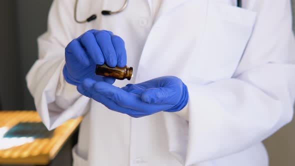 Senior Female Doctor in White Coat Takes Pills Out of a Jar