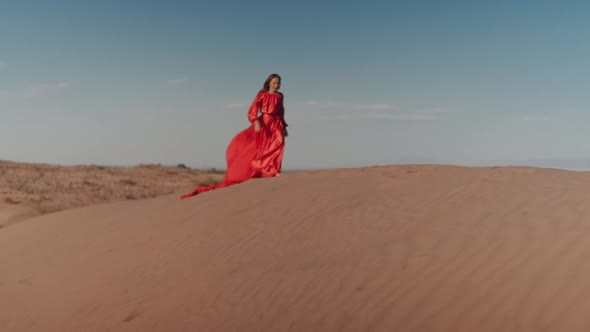 An Asian Woman in a Red Dress Dancing on Sand Dunes