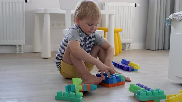 Baby Kid Is Playing Construction Kit Toys In Children Room On The Floor