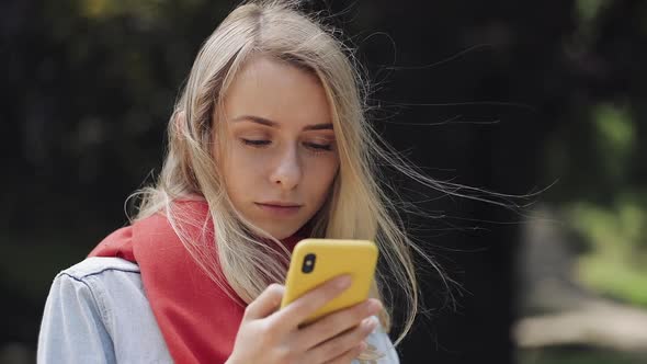 Portrait of Young Beautiful Woman Using App on Smartphone, Wearing in the Red Scarf Standing in the