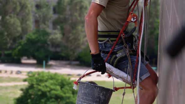 Industrial Climber in Equipment on Edge of Roof Prepares To Go Down on the Ropes