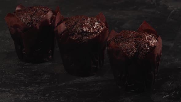 Ready-to-eat сhocolate muffins with crispy top on the gray background.