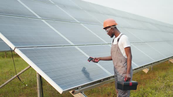 Close Up of Male Hand Holding Electronic Thermal Imager Near Solar Cell Outdoors