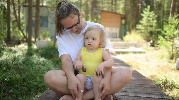 Little Cute Baby Toddler Girl Blonde with Curls on Mother's Arms