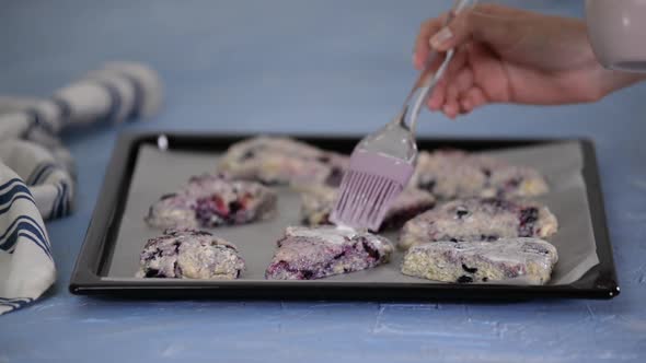 Housewife makes English scones with blueberries in the kitchen.