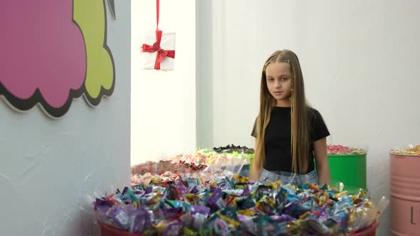 A Teenage Girl Looks at Colorful Snacks Candies on Supermarket Shelves Wanting to Buy for Herself