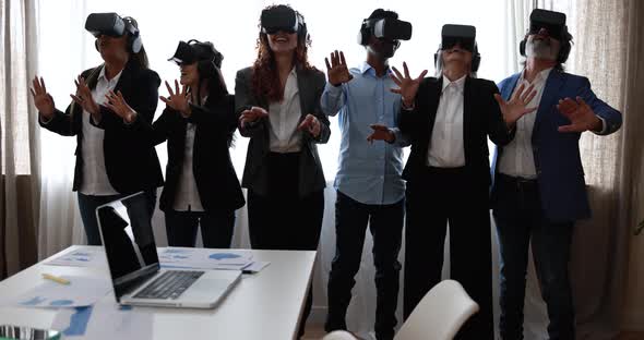 Multiracial teamwork having fun wearing virtual reality headset inside coworking office