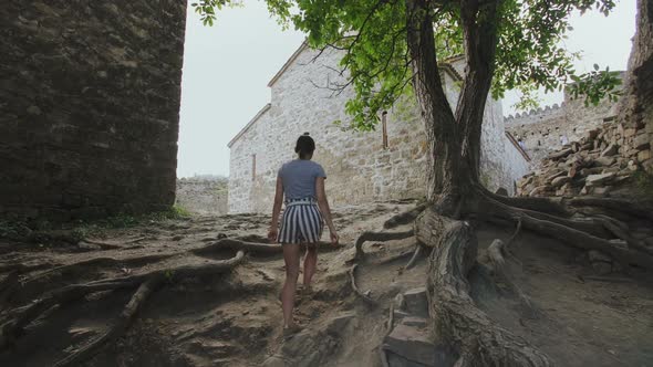 Girl Walks Path in Territory of Ancient Defensive Fortress Around a Church in Highlands Georgia