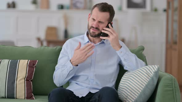 Angry Young Man Talking on Phone at Home