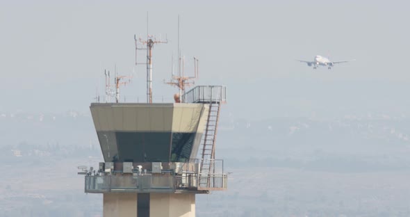 Airport control tower with airplane landing in the background