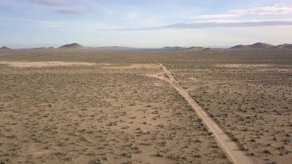 A lonely person stands all alone on a deserted road in the desert. Smooth aerial view flight panoram