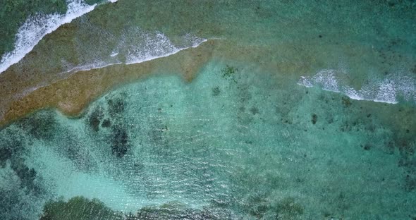 Luxury flying tourism shot of a white sandy paradise beach and aqua blue ocean background