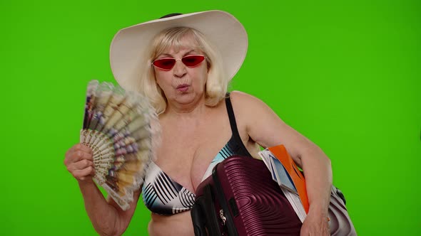 Senior Old Woman Tourist Exhales From Heat or Stuffiness Waves Hand Fan at Herself on Chroma Key