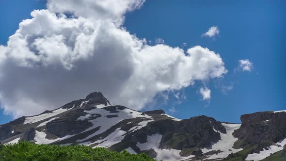 Oshten Mountain Partly Covered with Snow with Green Valley on Clear Sunny Day