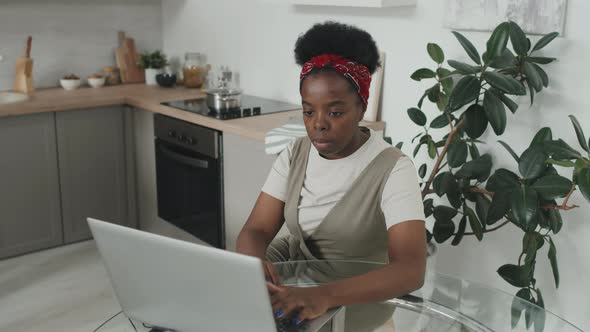 African-American Woman Working on Laptop in Kitchen