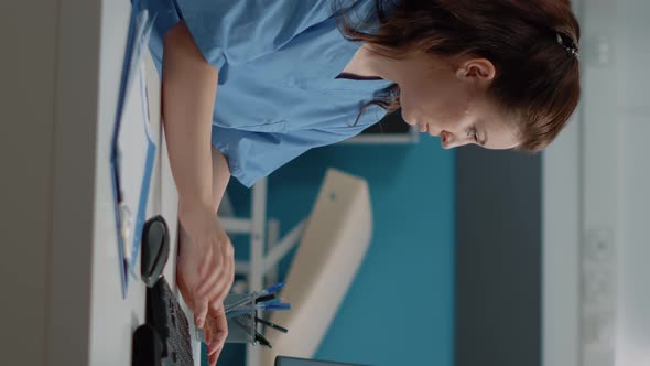 Vertical Video Medical Assistant Working on Computer with Patient Information