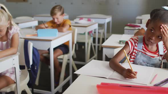 Video of thoughtful african american girl sitting at desk in classroom