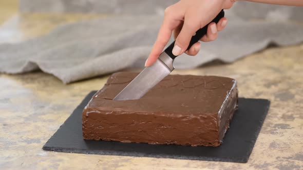 Female Hand Cutting Chocolate Cake with Knife