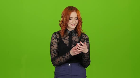 Girl Looks Into the Phone, Selects the Information She Needs. Green Screen