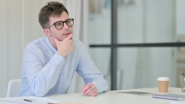 Young Man Sitting in Office Thinking