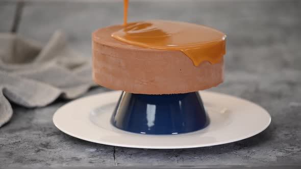 Pastry Chef Decorating Chocolate Mousse Cake with Caramel Mirror Glaze.