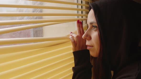 Close Up of Young Woman Watching Through Window Blinds at Home