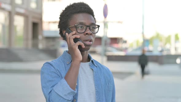 Angry Young African Man Talking on Phone Outdoor