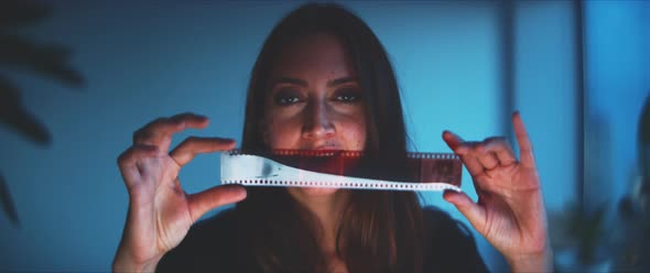 Woman holding a film strip, looking to the camera