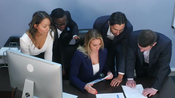 High Angle View of Creative Team Standing Around Table Discussing Business Ideas