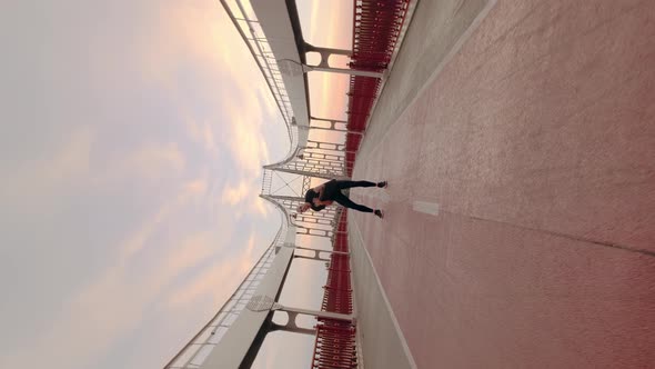 Young White Man in Black Sport Uniform Doing Warmup Before Run Pedestrian Bridge at Dawn