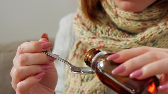 Sick Woman in Scarf Drinking Cough Syrup at Home