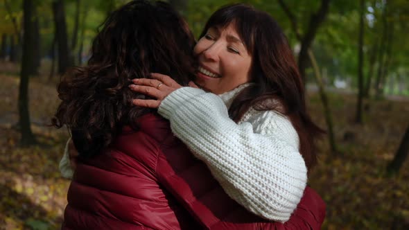 Mature Women Hugging Greeting in Autumn Park Outdoors