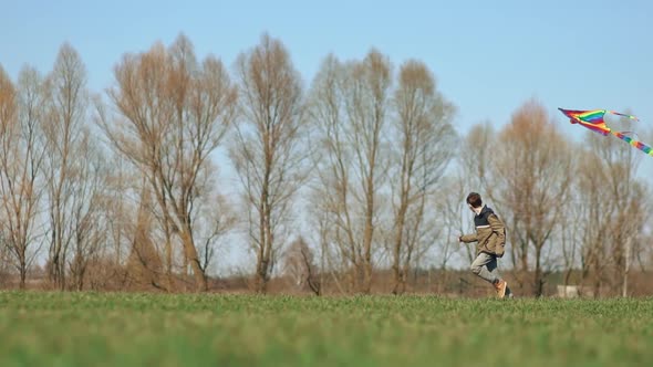 A Boy Runs Across a Green Field with a Kite