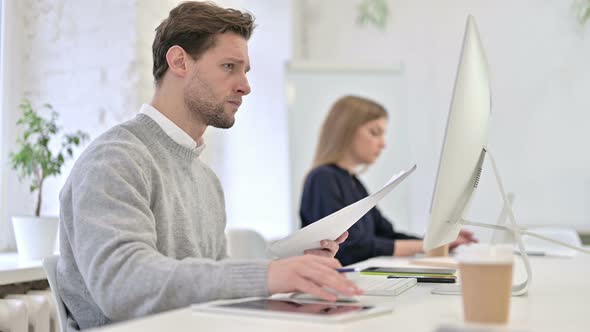 Serious Creative Man Reading Documents and Using Desktop